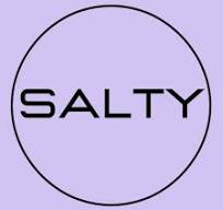 Desk with leather desk pad, walnut desk organizer, wireless keyboard and mouse, and porcelain mug.